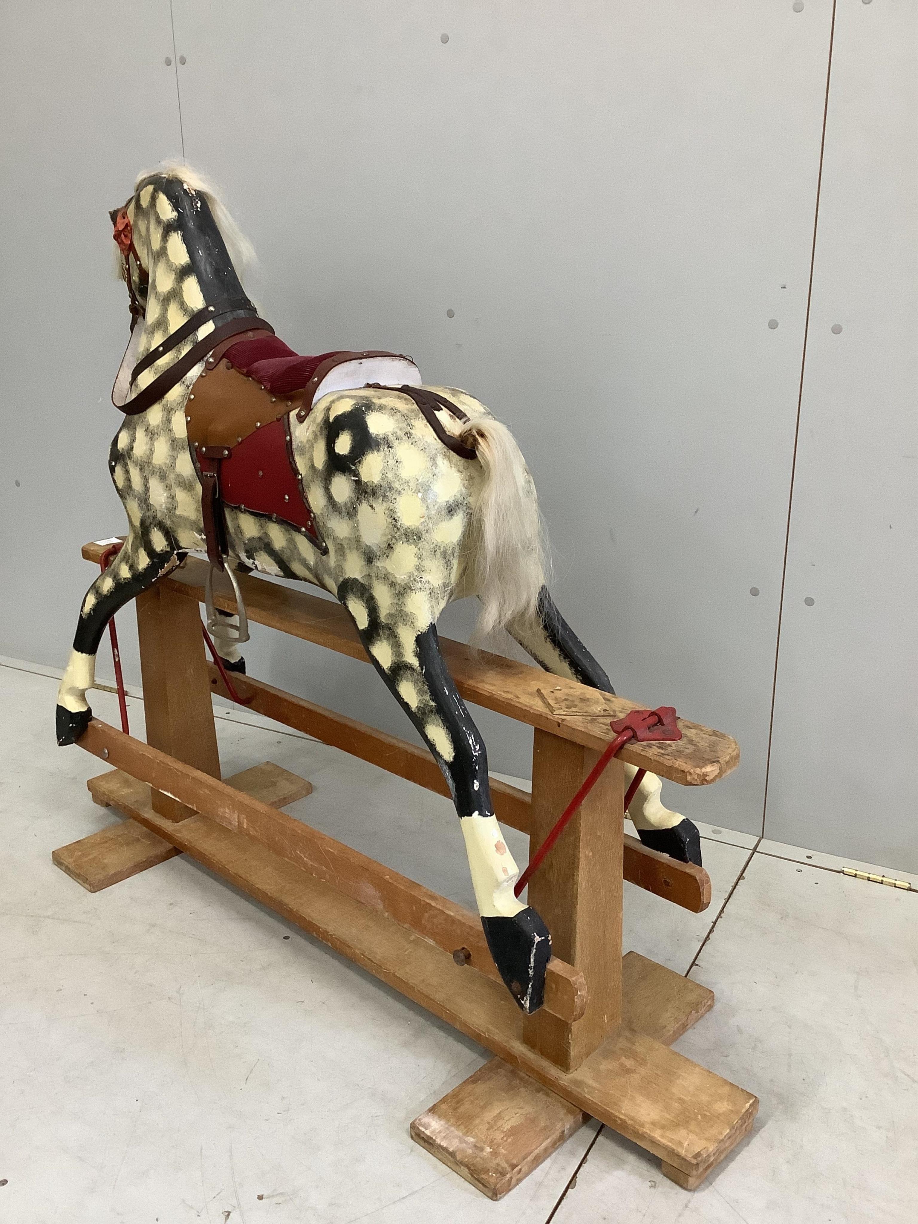 A mid-20th century dapple grey rocking horse, probably by Collinson, with corduroy and leather saddle and painted wooden body, 112cm high, the stand 137cm long. Condition fair, losses to the paint work and notable damage